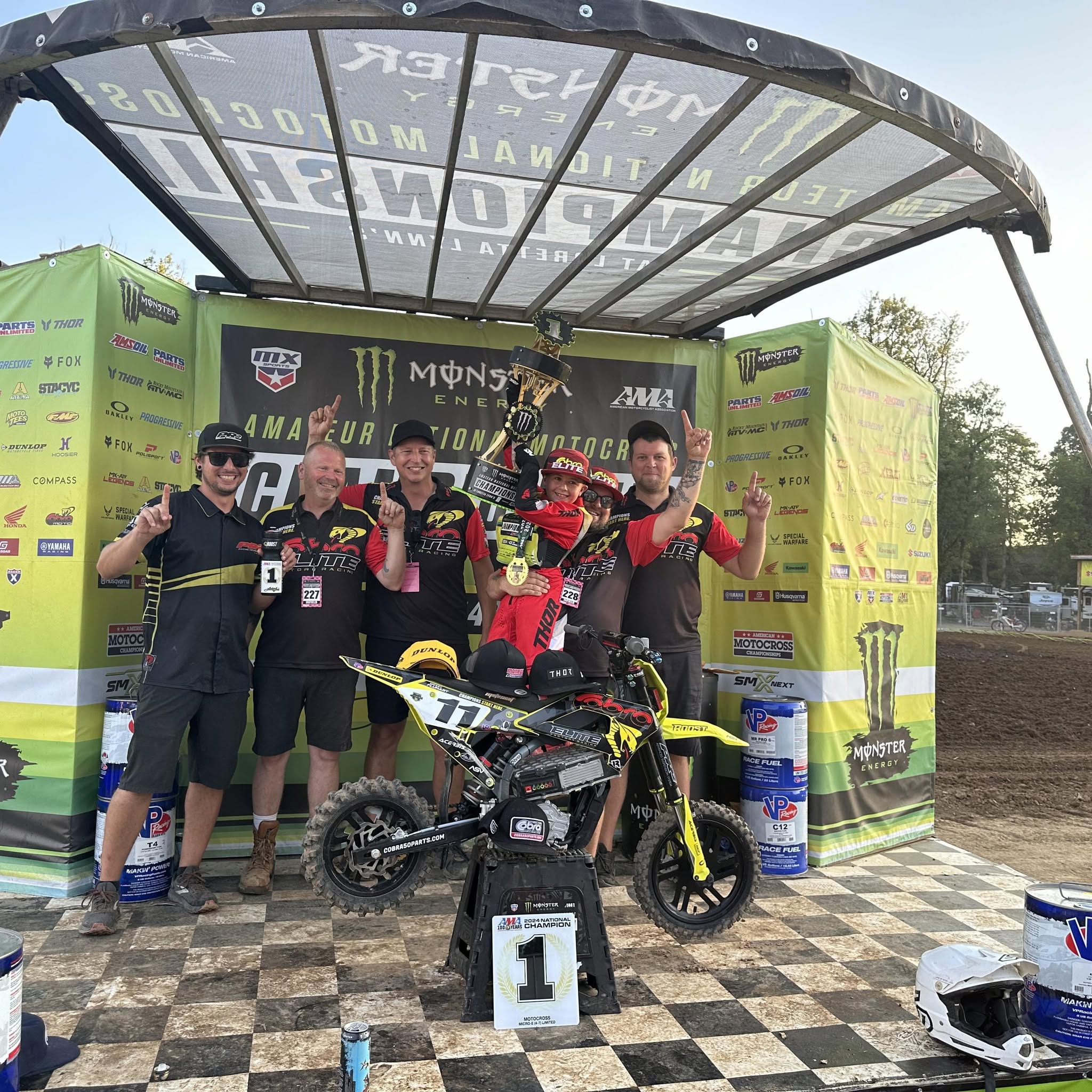 Mickey Fluhart celebrating his 2024 Loretta Lynn Micro-E national championship with his team and bike