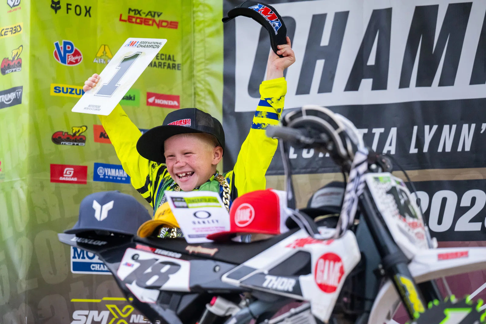 Wyatt Tedesco celebrating his 2025 Loretta Lynn national championship with his number one award and motorcycle